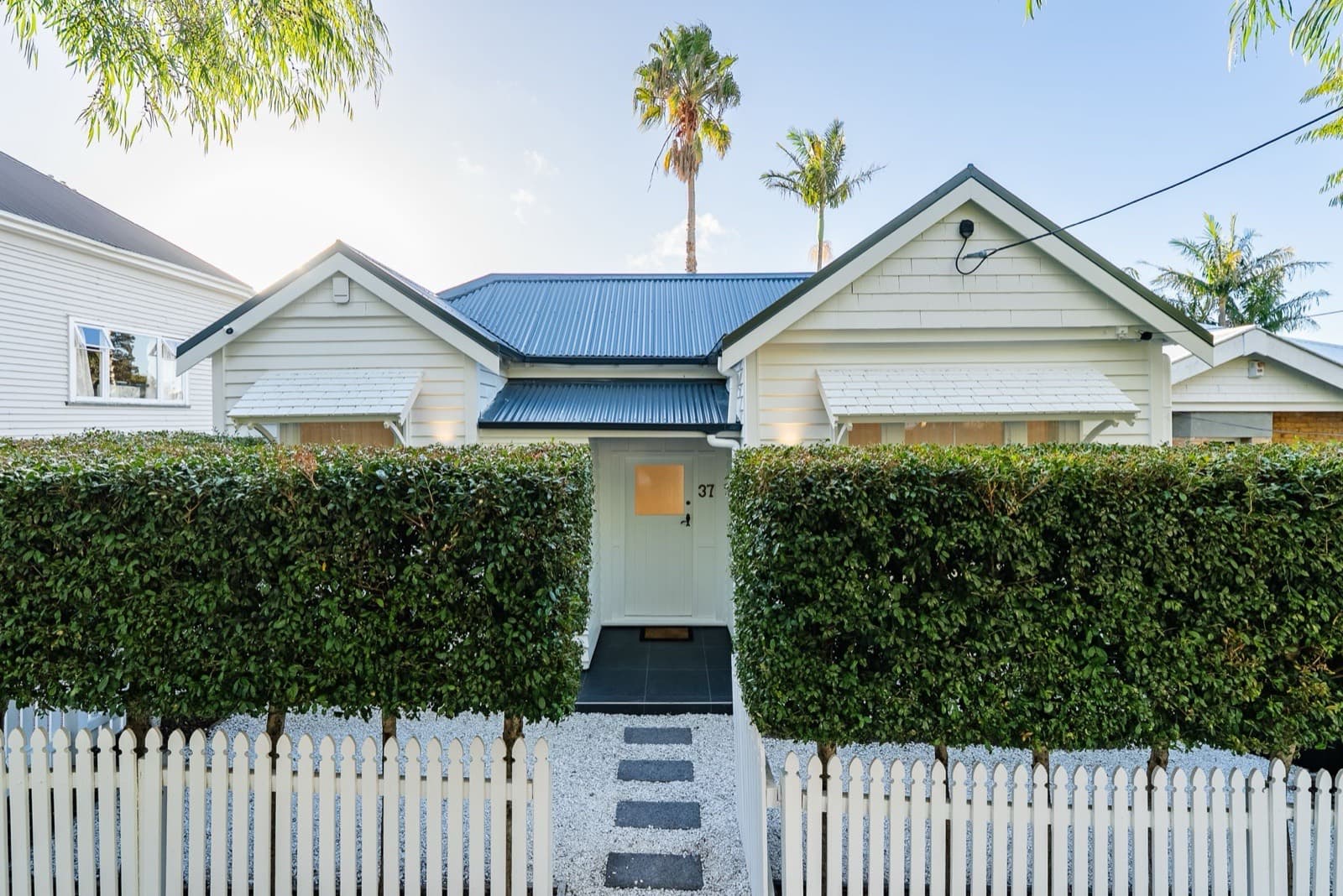 A restored Grey Lynn villa behind a clipped hedge and white picket fence