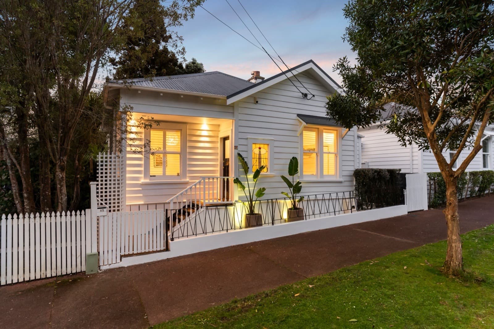 A Ponsonby villa at dusk, seen from the footpath behind its picket fence